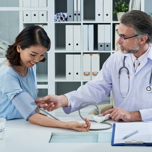 Doctor checking a woman's blood pressure