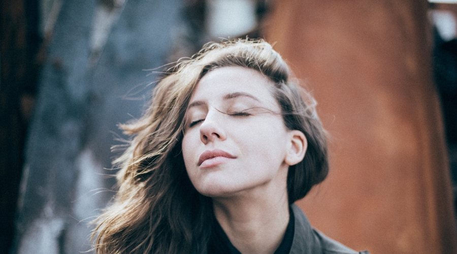 Woman breathing deeply with her eyes closed outdoors
