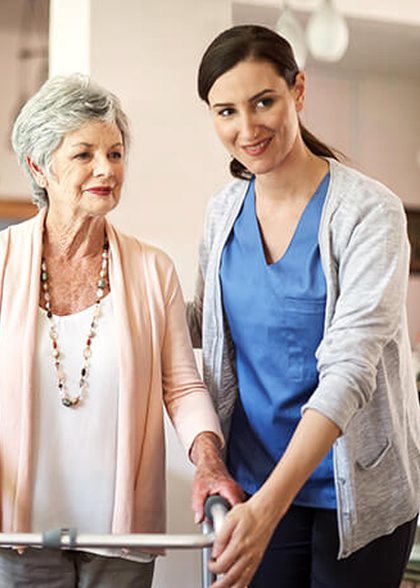 Nurse helping an older woman walk with a frame
